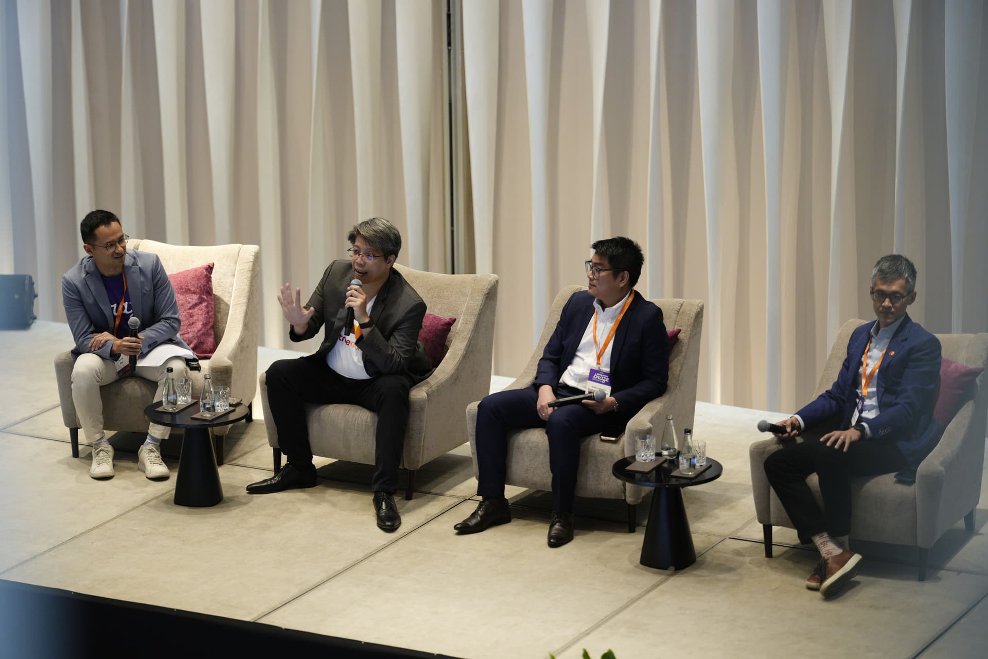a group of men are sitting in chairs on a stage talking to each other .
