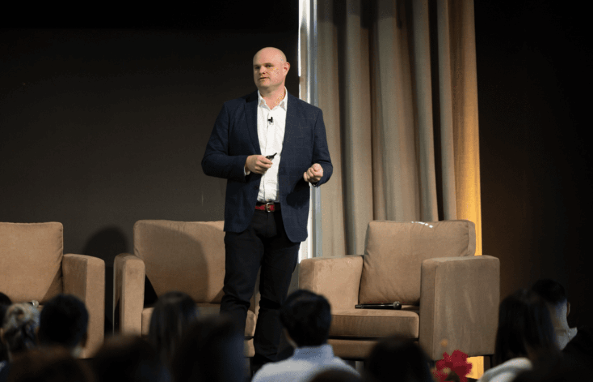 a man in a suit is giving a presentation in front of a crowd